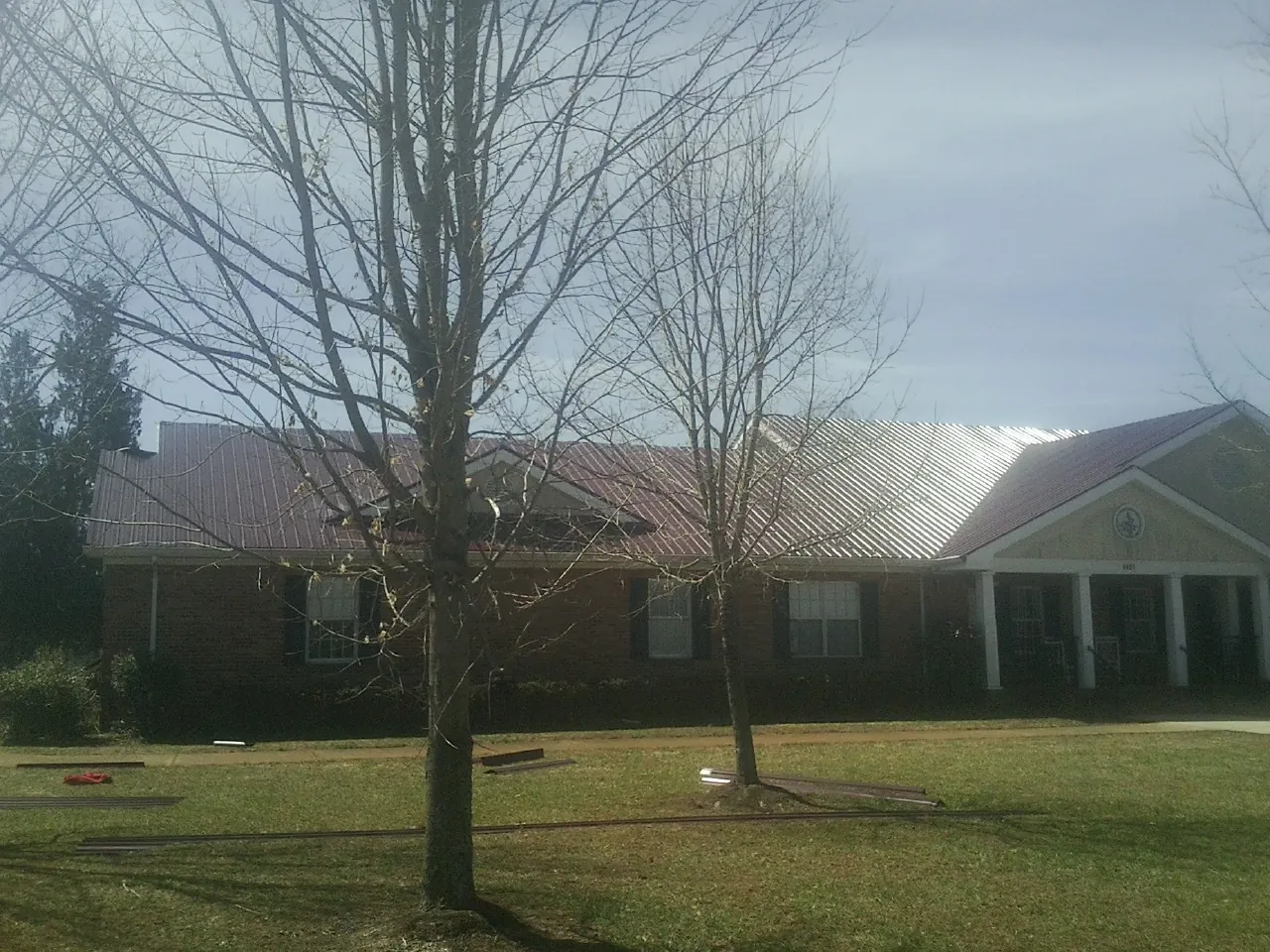 Red metal roof on a brick building seen from the front lawn in Horsham