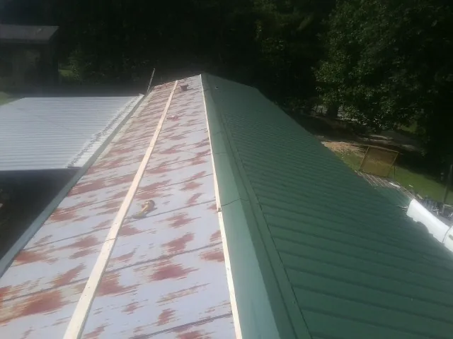 Old rusted panels beside newly installed green metal roofing — Wind Damage Roof Repair by Roofing Brothers in Horsham