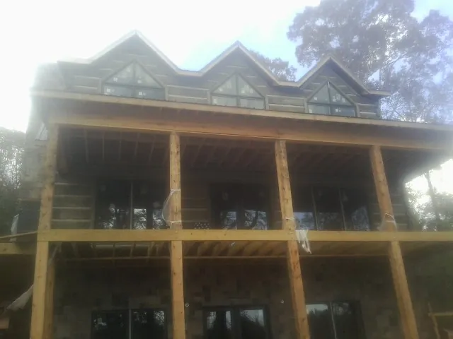 Dormers and porch framing on a large log home under construction — Roof Coating work by our crew in Horsham
