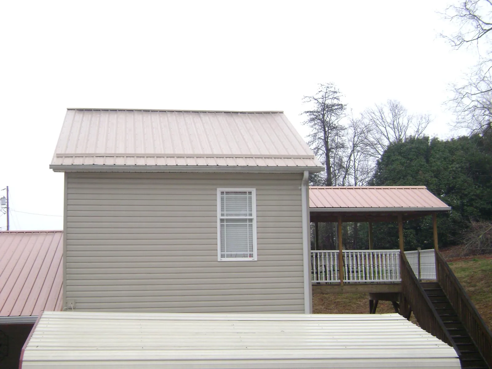 Tan metal roofs on a two story addition and attached porch, from a Roof Replacement job in Horsham