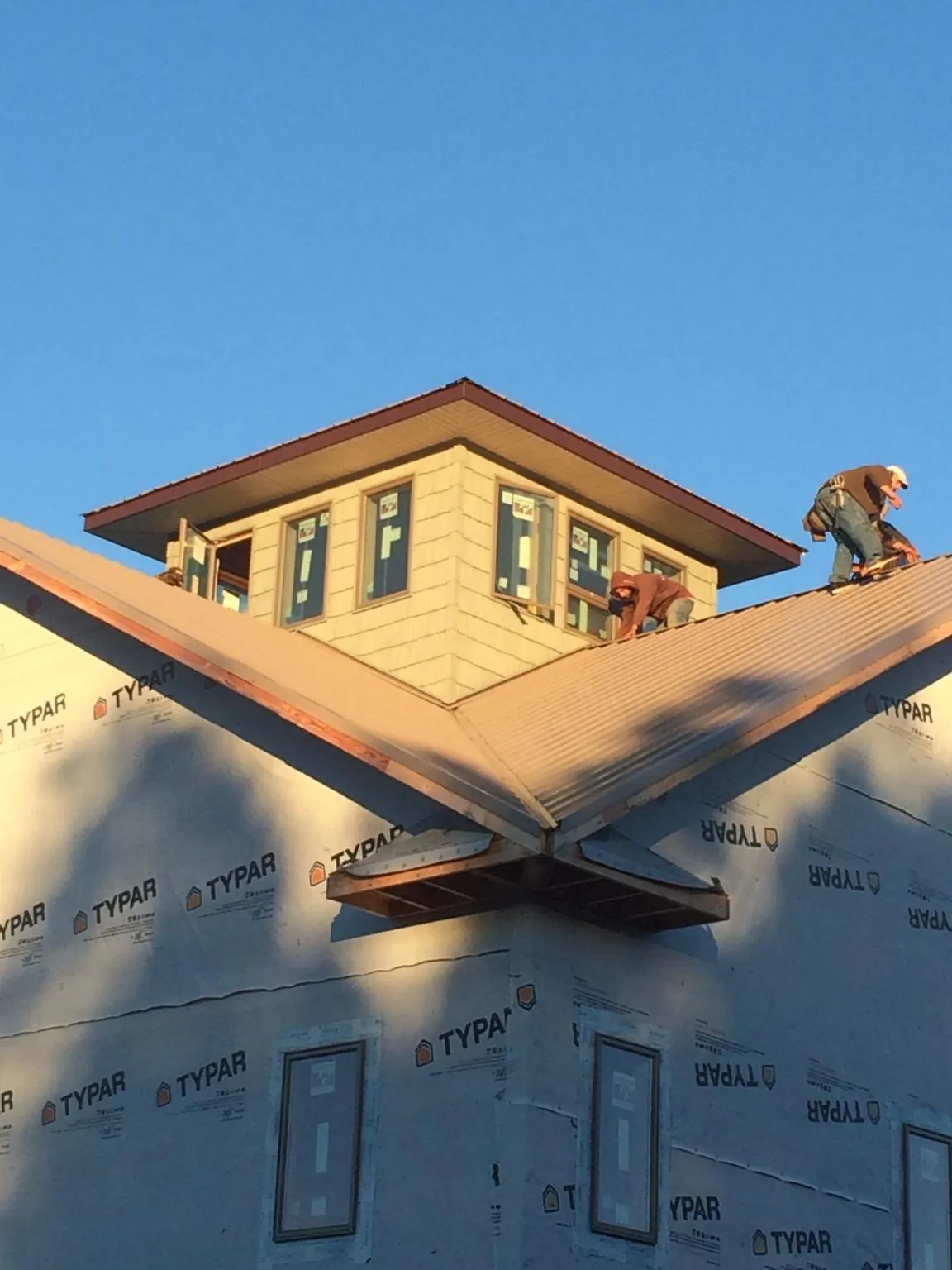 Roofers working around a rooftop cupola on a new metal roof at sunset — Roof Waterproofing in Horsham by Roofing Brothers